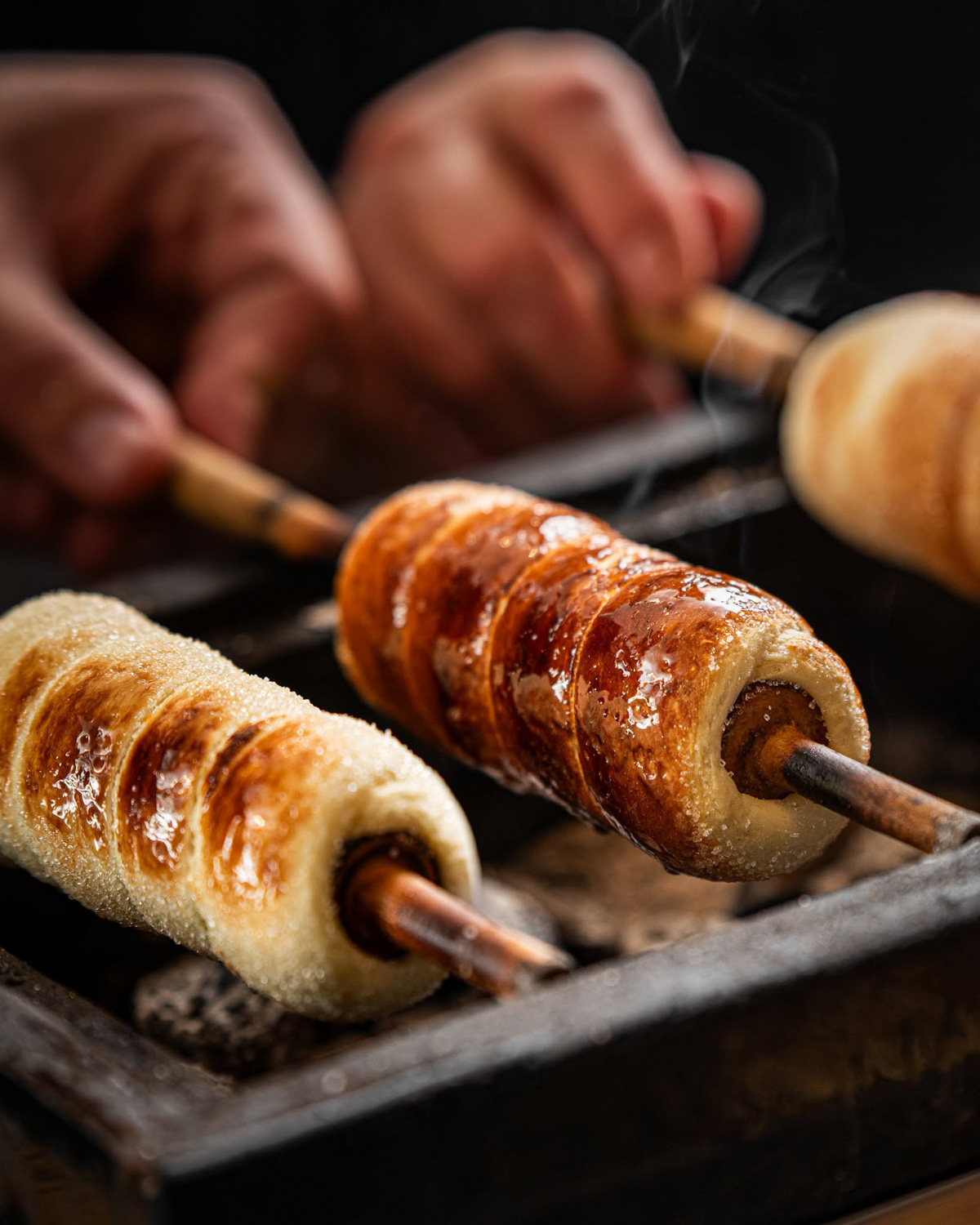 Traditional kürtőskalács being prepared over hot coals